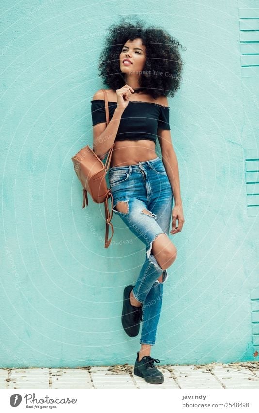 Young black woman with curly hair standing on blue wall Lifestyle Style Happy Beautiful Hair and hairstyles Face Human being Feminine Young woman