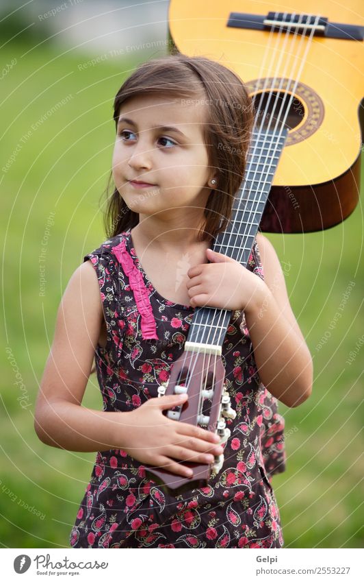 Girl with a guitar on the green grass Music Child School Human being Boy (child) Guitar Musical notes Flower Grass Green Pink girl student spanish handsome