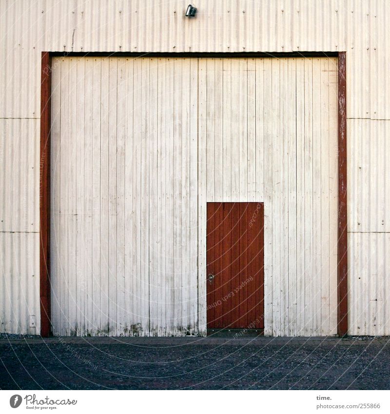 Get that door up. Nobody's illegal. Contentment Lamp Foliage plant Architecture Barn Warehouse Storage shed Door Street Red Symmetry Corrugated sheet iron Dusk