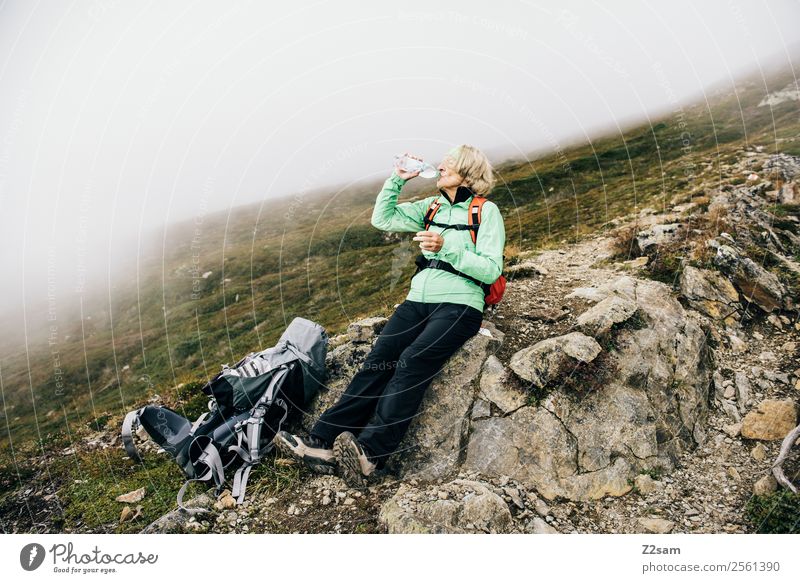 Pensioner drinks on the mountain top Mountain Hiking Female senior Woman 1 Human being 60 years and older Senior citizen Nature Landscape Autumn Bad weather Fog