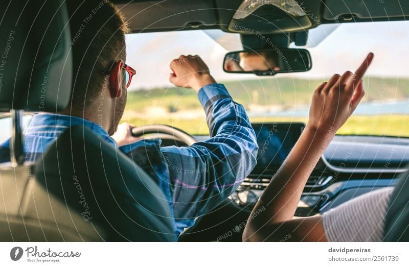 Happy young man driving car with his girlfriend Lifestyle Joy Leisure and hobbies Vacation & Travel Trip Adventure Music Human being Woman Adults Man Couple Arm