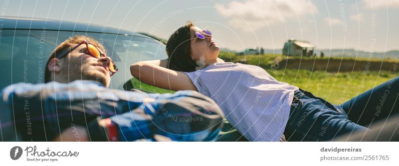 Young couple lying on the windshield Lifestyle Style Relaxation Calm Vacation & Travel Freedom Sunbathing Human being Woman Adults Man Couple Car Sunglasses