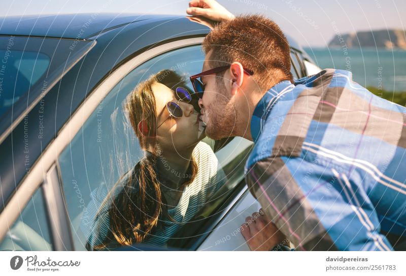 Young couple kissing through of glass car Lifestyle Vacation & Travel Adventure Far-off places Ocean Human being Woman Adults Man Couple Grass Meadow Coast