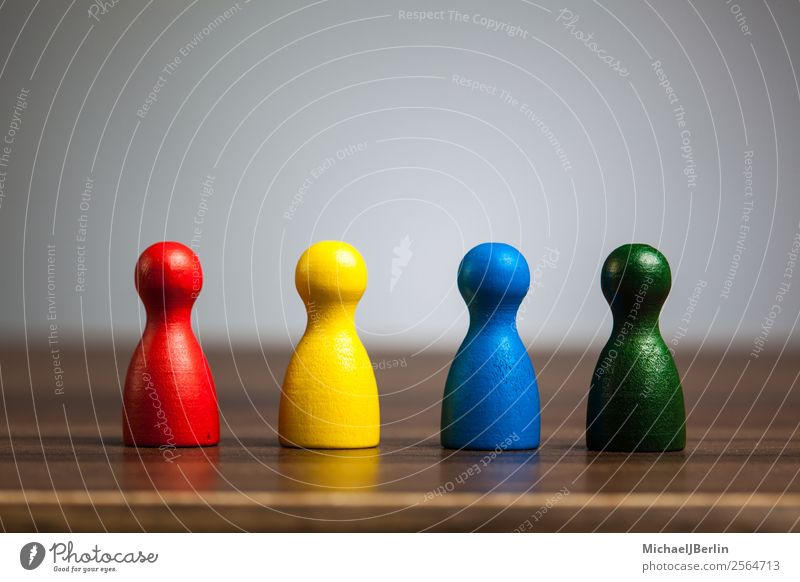 Four game figures on a table in various colours Playing Business Blue Multicoloured Yellow Green Red Symbols and metaphors Versatile Difference different