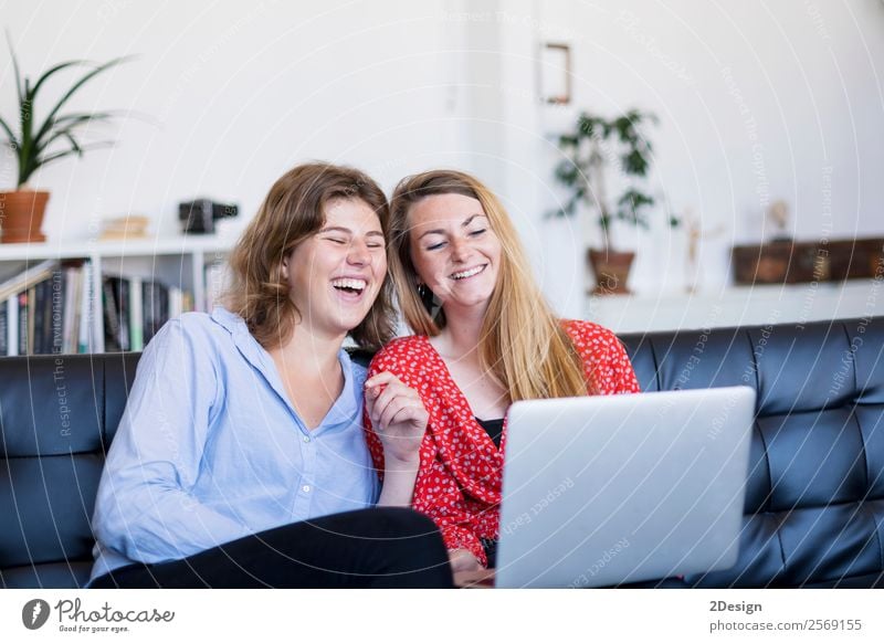 Two young women using computer while sitting on couch Lifestyle Shopping Happy Money Beautiful Relaxation House (Residential Structure) Sofa
