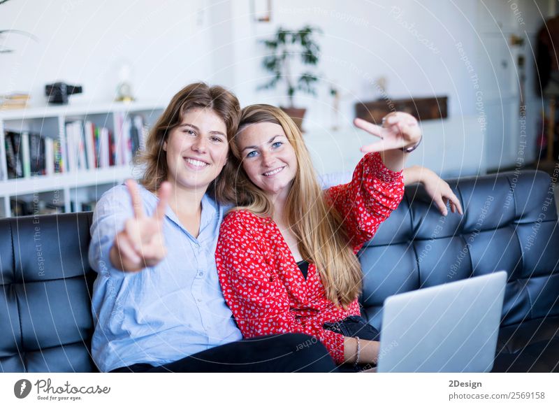 happy teenage girls sitting on a sofa Lifestyle Shopping Joy Happy Beautiful Contentment Leisure and hobbies Sofa Success To talk Computer Notebook Technology