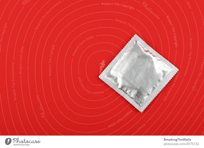 Close up condom silver wrap pack over red background Healthy Health care New Above Red Safety Protection Responsibility Caution Testing & Control Condom