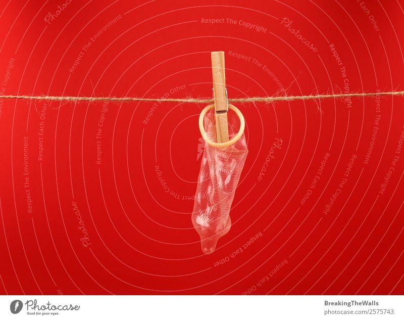 Close up condom hanging on washing line over red Healthy Health care Medication Wood Line String Red Safety Protection Responsibility Caution Colour