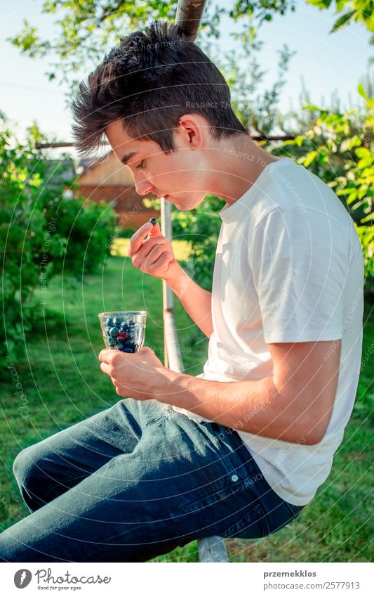 Teenager boy enjoying eating the fresh blueberries outdoors Food Fruit Nutrition Eating Organic produce Vegetarian diet Diet Bowl Lifestyle Summer Garden