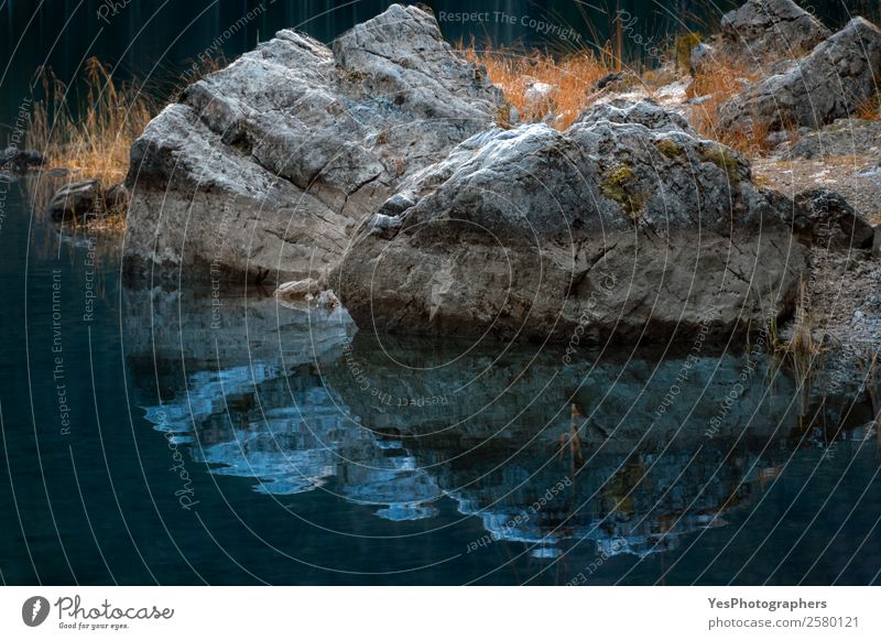 Rocks and dried grass reflected in water Harmonious Nature Water Autumn Stone Famousness Dark Perspective Symmetry Bavaria Eibsee lake Germany contemplative