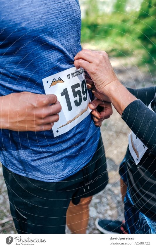 Trail athlete placing race number to her partner Lifestyle Sports Human being Woman Adults Man Friendship Couple Nature Forest Lanes & trails Stand Authentic