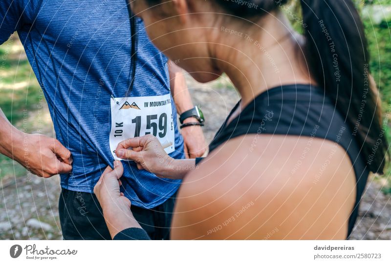 Trail athlete placing race number to her partner Lifestyle Sports Human being Woman Adults Man Friendship Couple Nature Forest Lanes & trails Stand Authentic
