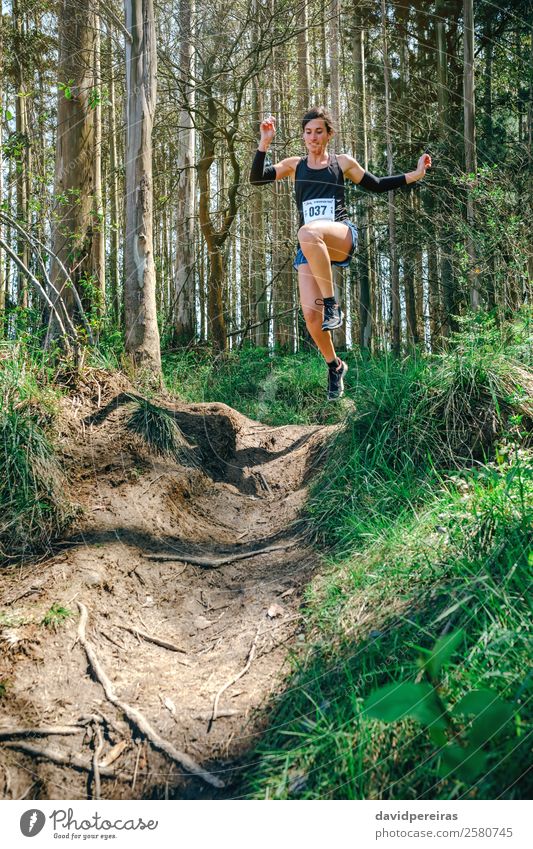 Woman jumping participating in trail race Lifestyle Sports Human being Adults Nature Tree Forest Lanes & trails Fitness Jump Authentic Speed Energy Competition