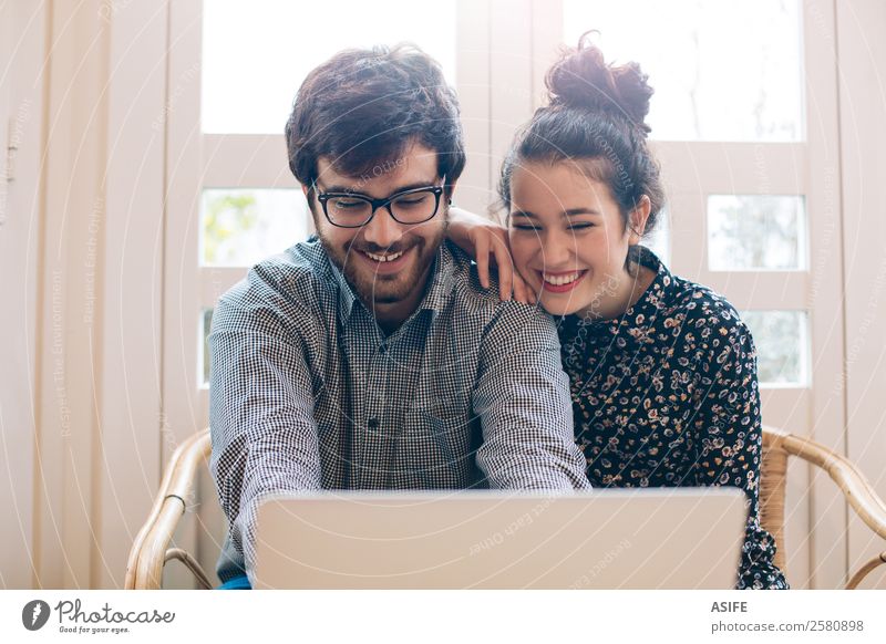 Attractive couple using a laptop Joy Happy Computer Notebook Technology Internet Woman Adults Man Couple Beard Smiling Laughter Love Sit Together Bright Modern