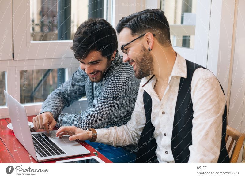 Two young modern men using a laptop and a tablet in a cafe bar Coffee Joy Happy Study Work and employment Business Meeting Computer Notebook Screen Technology