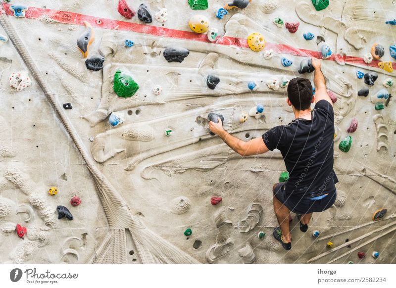 A Man practicing rock climbing on artificial wall indoors Lifestyle Joy Leisure and hobbies Sports Climbing Mountaineering Adults Hand Fingers Feet 1