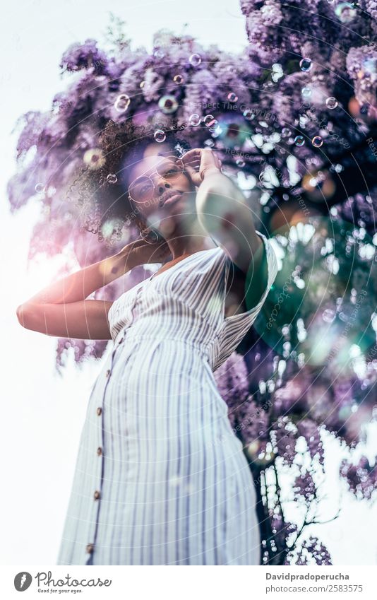 Happy young black woman surrounded by flowers Lifestyle Beautiful Relaxation Summer Garden Woman Adults Nature Tree Flower Blossom Dress Sunglasses Smiling
