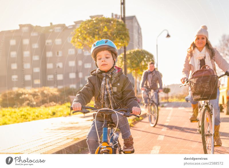 Happy family with a child riding bicycles by the city Lifestyle Relaxation Leisure and hobbies Vacation & Travel Sun Winter Sports Child Boy (child) Woman