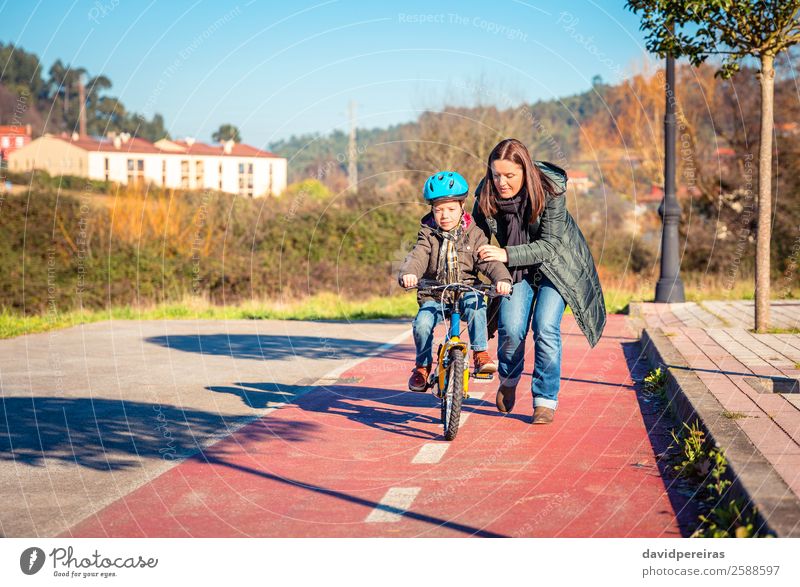 Mother teaching her son to ride a bicycle Lifestyle Joy Happy Leisure and hobbies Playing Sun Winter Sports Success Cycling Child School Boy (child) Woman