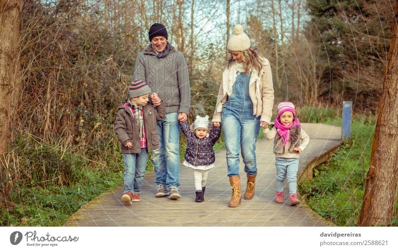 Happy family walking together over pathway into the forest Lifestyle Joy Leisure and hobbies Winter Child Boy (child) Woman Adults Man Parents Mother Father