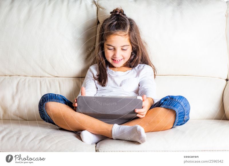 Little girl using a tablet at home Lifestyle Happy Beautiful Leisure and hobbies Playing Sofa Entertainment Education Child Study Cellphone Computer Notebook