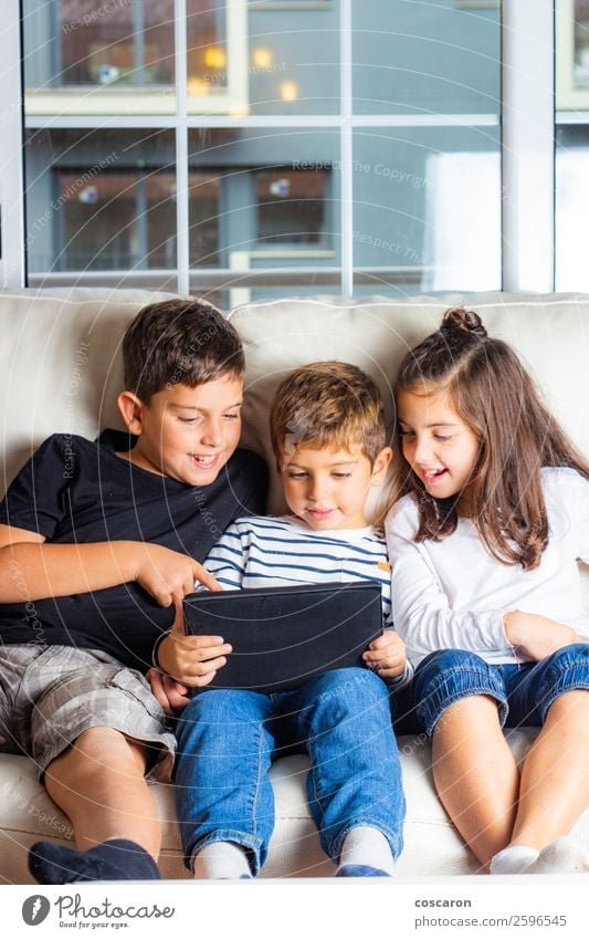 Three kids using a tablet at home Lifestyle Joy Happy Beautiful Leisure and hobbies Playing Sofa Education Child Study Student Cellphone Computer Notebook