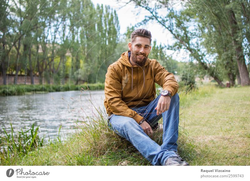 Smiling young man, sitting on the riverbank. Lifestyle Young man Youth (Young adults) 1 Human being 18 - 30 years Adults Nature Autumn Beautiful weather Grass