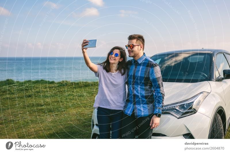 Young couple doing a selfie on the car Lifestyle Joy Happy Beautiful Vacation & Travel Trip Ocean PDA Human being Woman Adults Man Couple Grass Coast Car