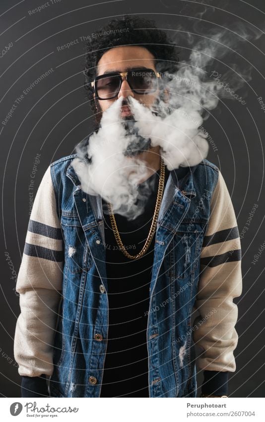 Young man with sunglasses blowing a cloud of smoke. Lifestyle Elegant Happy Technology Human being Man Adults Clouds Sunglasses Beard Black Cigarette Electronic