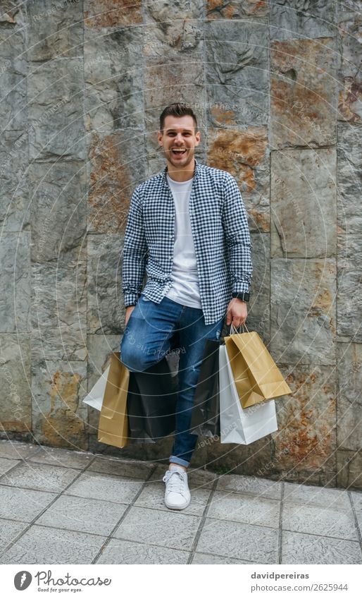 Young man with shopping bags Lifestyle Shopping Happy Hair and hairstyles Relaxation Leisure and hobbies Human being Man Adults Fashion Jeans Sneakers Smiling