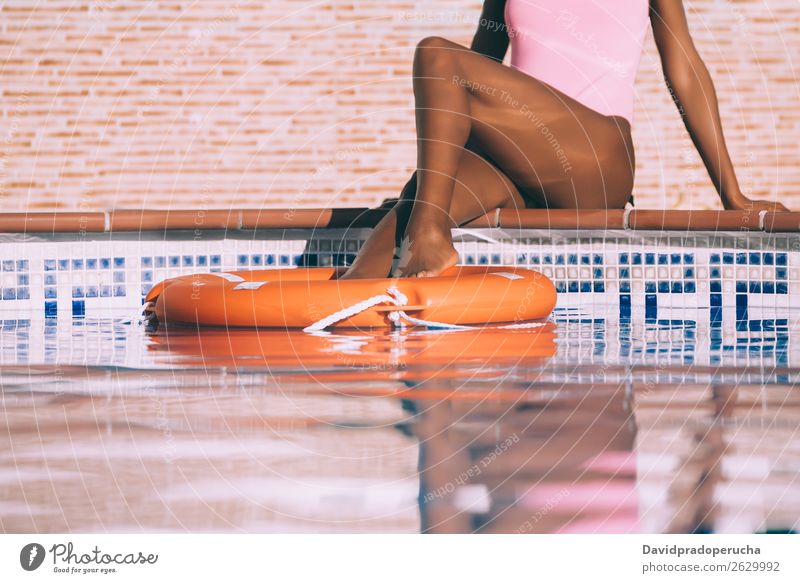 Woman legs in a swimming pool with lifesaver Ethnic Swimming pool Summer Lifeguard Sunbathing Barefoot Legs Pedicure Relaxation Skin tan Water Unrecognizable