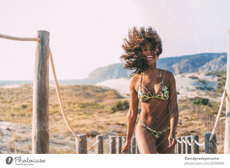 Beautiful young woman wearing a bikini in a wooden foot bridge at the beach Beach Woman Bikini Black Bridge Background picture Coast Curly hair Destination Girl