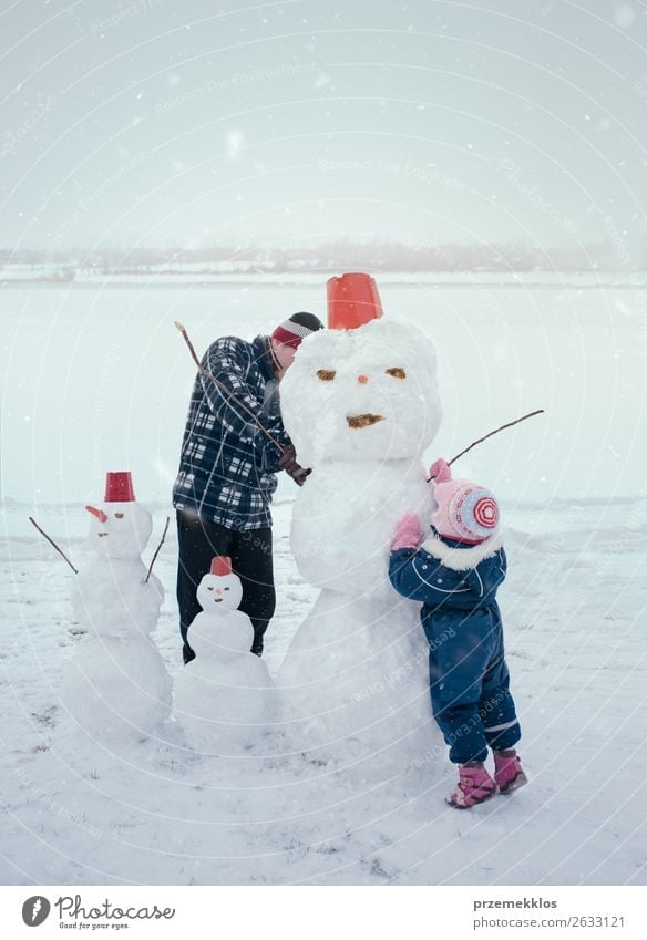 Man and his little daughter making a snowman, spending time together outdoors, having fun on snow in wintertime Lifestyle Joy Happy Leisure and hobbies Playing