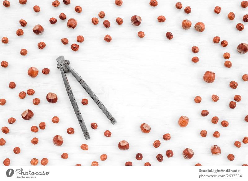 Nutcracker and hazelnuts on white background with copy space Nutrition Eating Vegetarian diet Diet Table Kitchen Wood Metal Fresh Natural Brown White Colour
