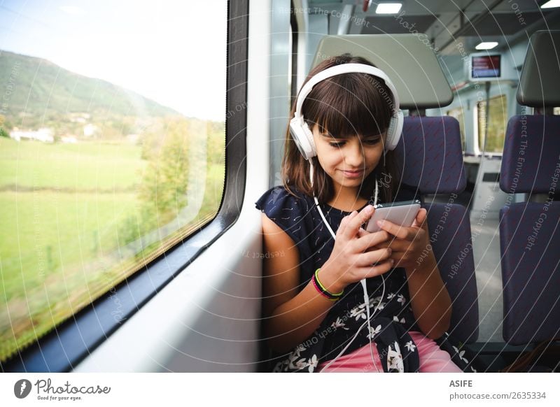 Little girl with headphones and smart phone travelling by train Joy Happy Beautiful Leisure and hobbies Vacation & Travel Trip Music Child Headset PDA