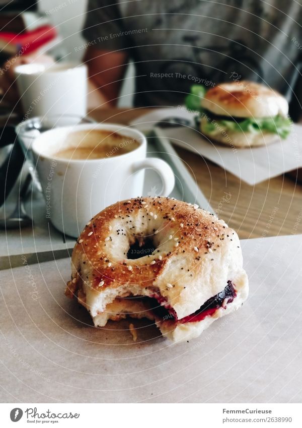 Two people having breakfast bagels in a cafe Lifestyle Young man Youth (Young adults) Man Adults 1 Human being To enjoy Bagel bitten off Coffee Café Breakfast
