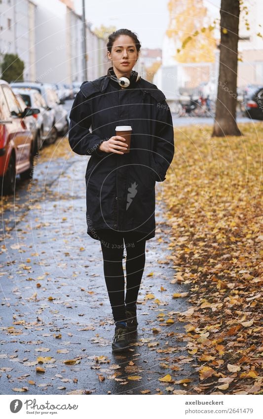 young woman walking along city street in autumn Drinking Hot drink Coffee Mug Lifestyle Style Leisure and hobbies Human being Feminine Young woman