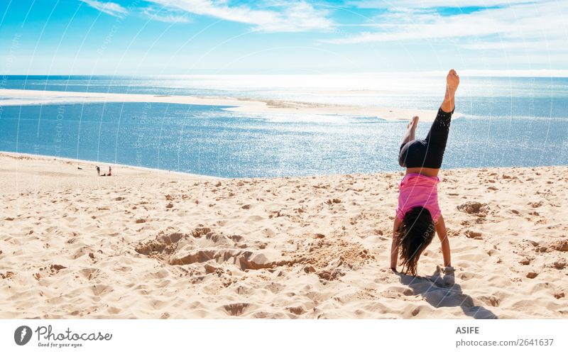 Happy little girl doing a handstand on the beach Joy Beautiful Leisure and hobbies Playing Vacation & Travel Tourism Summer Beach Ocean Child Woman Adults