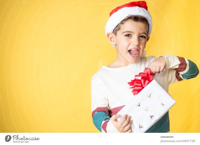 Little kid with a gift on a yellow background on Christmas Day Lifestyle Style Design Joy Happy Beautiful Winter Feasts & Celebrations Christmas & Advent Child