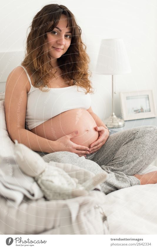 Pregnant woman touching her belly Lifestyle Happy Beautiful Leisure and hobbies Sofa Human being Baby Woman Adults Parents Mother Family & Relations Touch Love