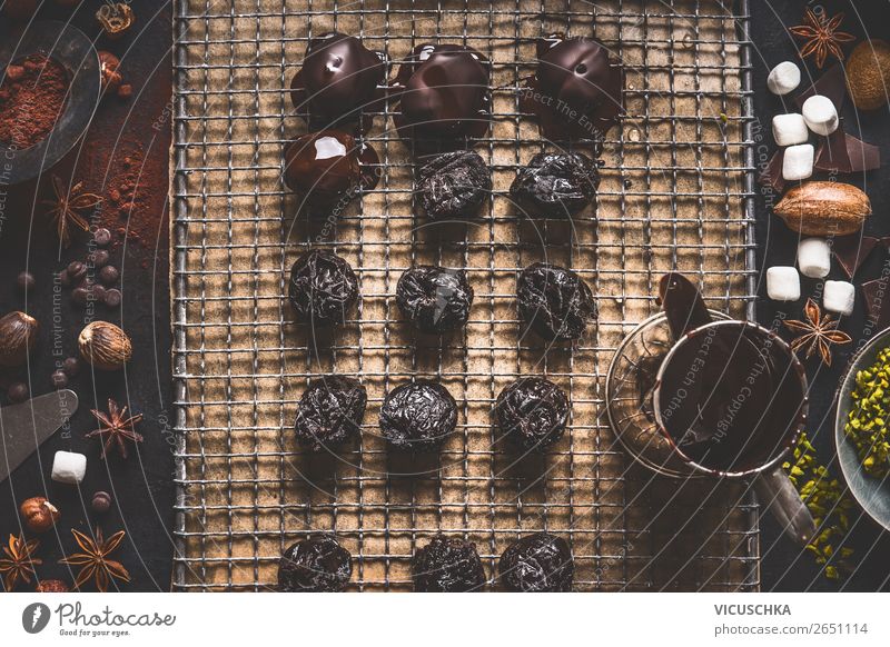 Homemade pralines and truffles on dark kitchen table background with melting chocolate and ingredients, top view homemade cocoa rustic powder healthy food vegan