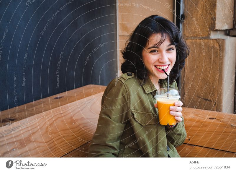 Happy young woman drinking a fruit smoothie in a bar terrace Vegetable Fruit Drinking Juice Lifestyle Joy Beautiful Woman Adults Terrace Container Jacket
