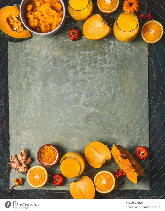 Orange color smoothie ingredients background for cold season: pumpkin, orange fruits, ginger, turmeric and persimmon fruits , top view, frame, copy space. Healthy mood and energy smoothie drinks