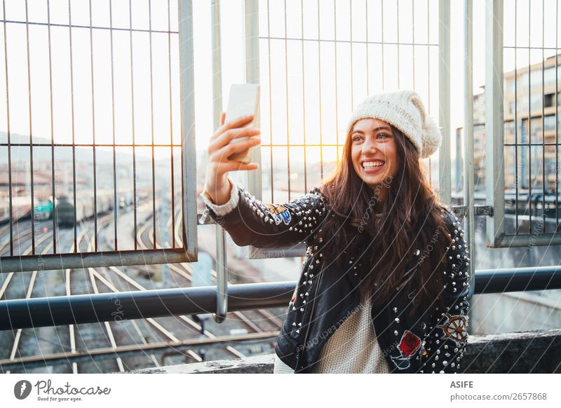 Selfie girl in the city at sunset Happy Beautiful Winter PDA Technology Woman Adults Youth (Young adults) Autumn Train station Street Railroad tracks Fashion