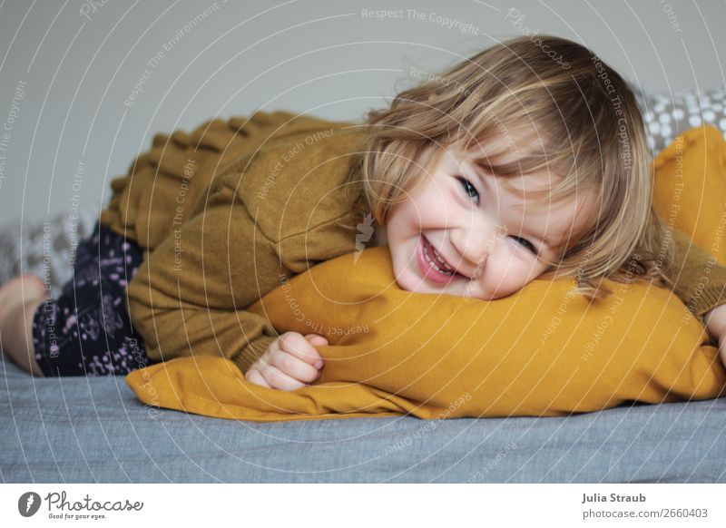 Toddler lying on a pillow and laughing Bed Bedroom Feminine Girl Infancy 1 Human being 1 - 3 years Pants Sweater Brunette Blonde Curl Bangs Movement Laughter
