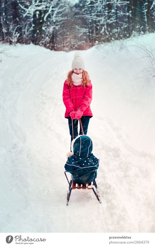 Teenage girl pulling sled with her little sister through forest Lifestyle Joy Happy Winter Snow Winter vacation Human being Child Girl Young woman