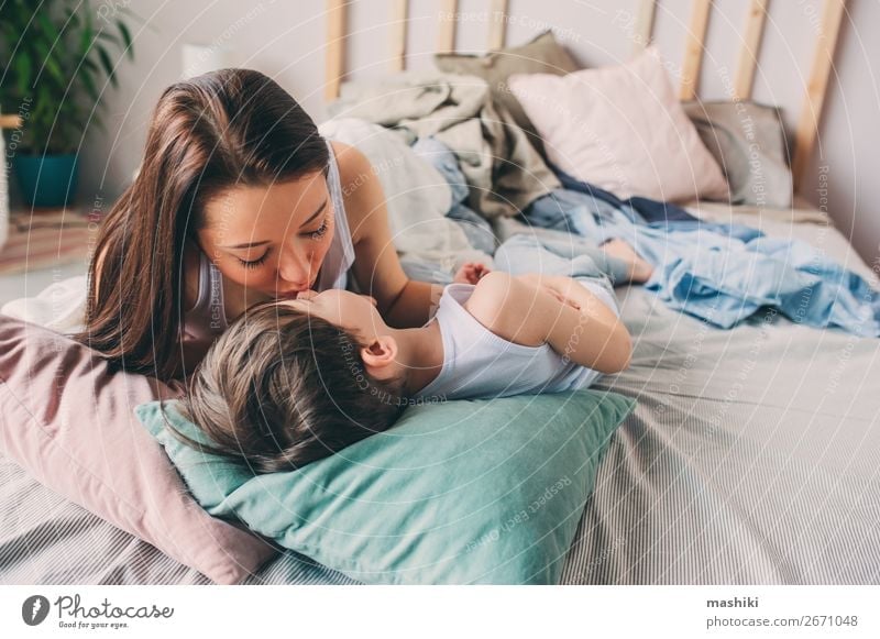 mother kisses her toddler son in bed for good night Lifestyle Joy Happy Relaxation Playing Bedroom Child Toddler Boy (child) Parents Adults Mother