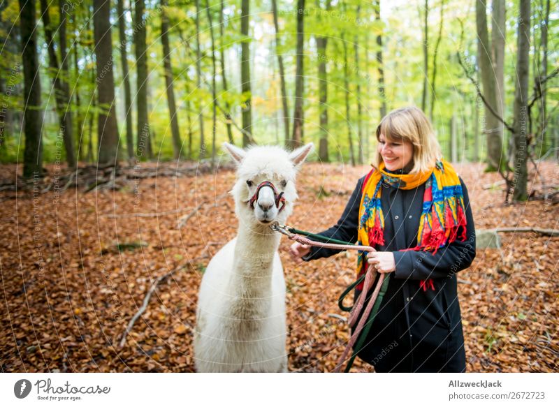 young woman leads white alpaca for a walk in the forest Colour photo Exterior shot Day Blur Central perspective Portrait photograph Animal portrait Forward