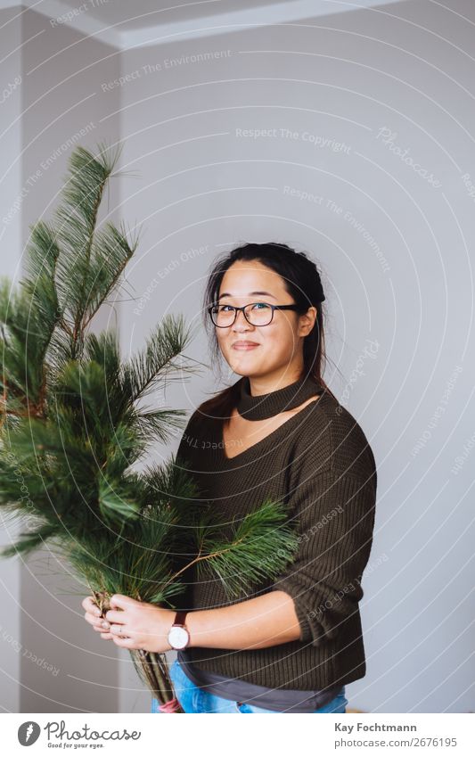 Smiling Asian holds silk pine in her hands Lifestyle Living or residing Flat (apartment) Decoration Christmas & Advent Work and employment Trade Floristry Woman