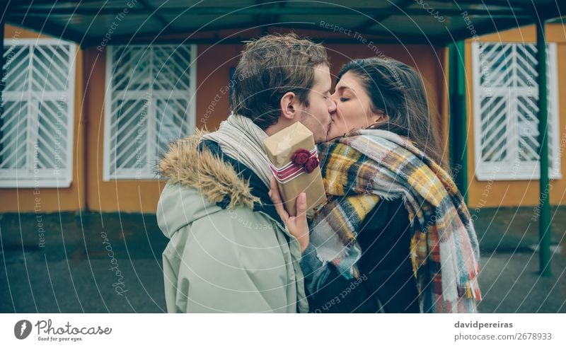 Woman with gift box in hand embracing and kissing to boyfriend Lifestyle Happy Beautiful Winter Feasts & Celebrations Birthday Human being Adults Man Couple